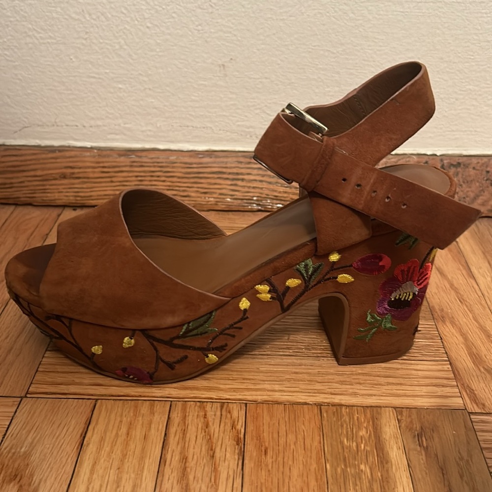 Brown suede platform sandals with embroidery on the platform.